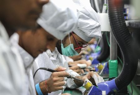 　２月１３日、インドのチャンドラセカール電子・情報技術省副大臣はシタラマン財務相に送った１月３日付の書簡と説明資料で、同国はスマートフォンの輸出競争で中国やベトナムに敗北する恐れがあると指摘、関税の引き下げによる世界的企業の誘致へ向け「迅速に行動」しなければならないと訴えた。写真は携帯電話機のプリント基板にワイヤをはんだ付けする作業員。インドのノイダにある工場で２０１８年１０月撮影（２０２４　ロイター／Anushree Fadnavis）
