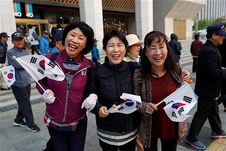イベント好きな韓国の人たちは南北首脳会談をそれぞれの立場から見つめた。写真は板門店に向かう文在寅大統領を見送りにきたご婦人。REUTERS/Jorge Silva