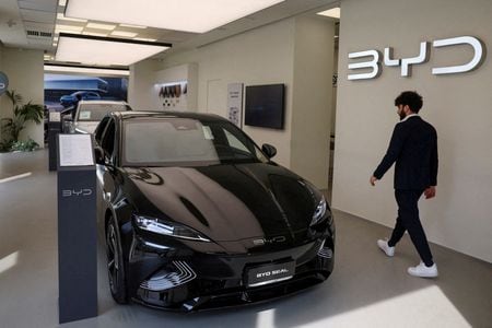 中国の自動車メーカー、比亜迪（ＢＹＤ）は第２・四半期の電気自動車（ＥＶ）販売台数が２１％増加し、米テスラとの差を縮める見通し。写真はＢＹＤ車とその横を歩く人。イタリア・ミラノで３月撮影。（2024年 ロイター/Claudia Greco/File Photo）