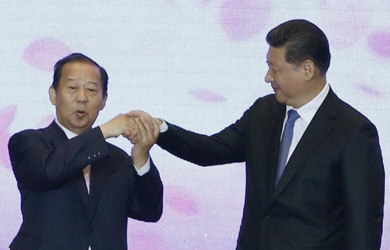 2015年、舞台で習近平国家主席と握手する二階幹事長(3000人の訪中団随行)　Kim Kyung Hoon-REUTERS