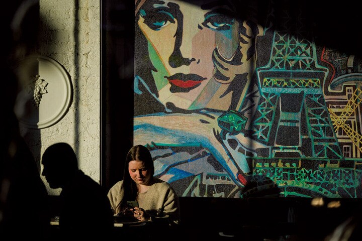 モスクワのカフェで壁画を背景に日なたぼっこをする人々