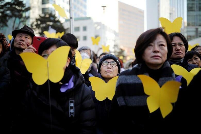 韓国の憲法裁判所は、慰安婦問題の解決を確認した2015年の日韓合意は違憲だと元慰安婦らが訴えていた訴訟で原告の訴えを却下した。写真は元慰安婦の葬儀に際し、手向けるための黄色い蝶を持つ人々。韓国ソウルで2月撮影（2019年　ロイター／Kim Hong-Ji）