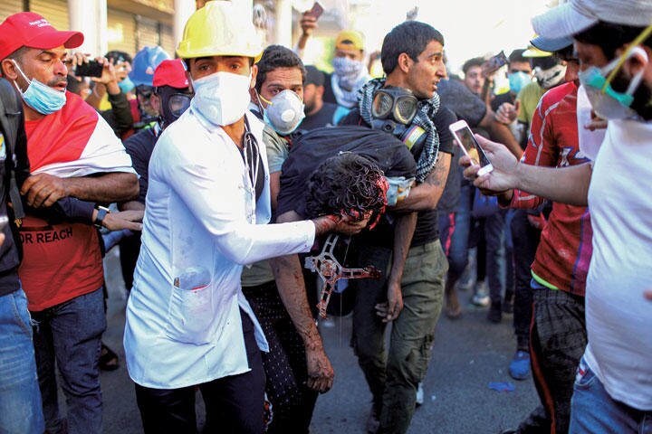 頭から血を流す抗議者を救助する医療関係者　AHMED JADALLAH-REUTERS