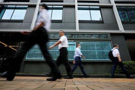　５月２３日、午前の東京株式市場で日経平均は、前営業日比２９６円３８銭高の３万８９１３円４８銭と反発して取引を終えた。写真は株価ボードの前を歩く人々。都内で２０２０年１０月撮影（２０２４　ロイター／Issei Kato）