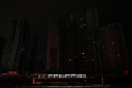 　１１月２４日、ロシアによるミサイル攻撃で戦争開始以来最大規模の停電に見舞われたウクライナでは、首都キーウ（キエフ）を含む各都市で徐々に電力が回復している。写真はキーウで２３日、電気の点いていない集合住宅の前を通る路面電車（２０２２年　ロイター／Valentyn Ogirenko）
