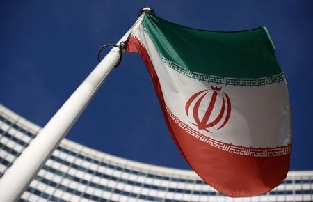 国際原子力機関（ＩＡＥＡ）は、イランが中部ナタンズの地下施設で、新型の遠心分離機「ＩＲ４型」を使ったウラン濃縮作業を開始したとする報告書をまとめた。写真はイラン国旗、後方がＩＡＥＡ本部、１日撮影（２０２１年　ロイター／Lisi Niesner）