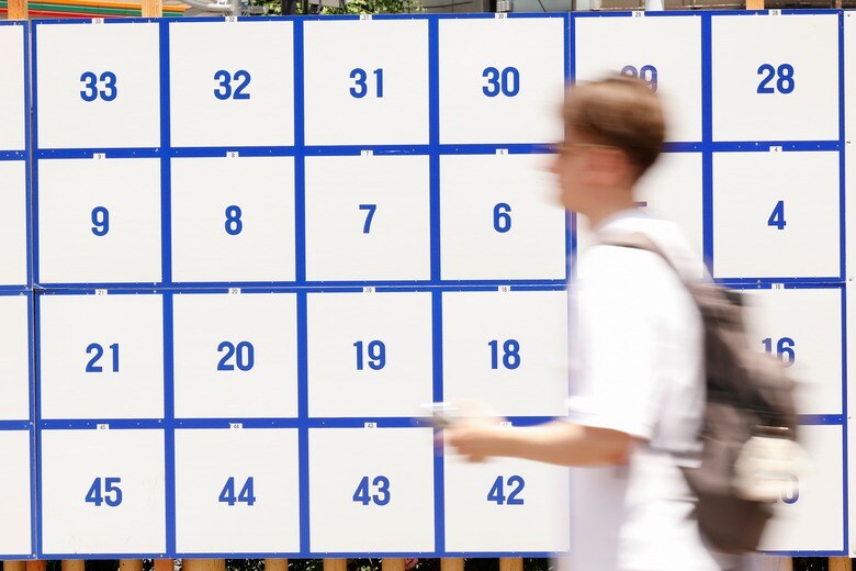 東京都議選の選挙掲示板の前を通る通行人（6月5日）　　Rodrigo Reyes Marin／SOPA Images via Reuters