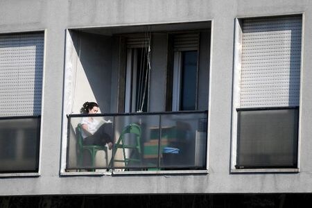 　イタリア政府は、新型コロナウイルス感染拡大を防止するための都市封鎖（ロックダウン）措置を５月３日まで延長する計画だ。写真はミラノで、ベランダで本を読む女性。９日撮影（２０２０年　ロイター/Daniele Mascolo）