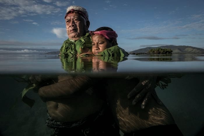 「単写真（東南アジア・オセアニア）」部門　『沈むことなく闘う』 　Eddie Jim　南太平洋の島国フィジーのキオア島の長老が記憶をたどり、少年時代に海岸線があった地点に孫と共に立つ。世代を超える海面上昇の影響を表現した。同島には1940年代に隣国ツバルから移住した人々が多いが、海面上昇のせいでさらに住民が故郷を離れる事態も懸念される