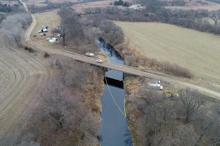 　米カンザス州で発生した「キーストーン」原油パイプラインの流出事故について、地元当局は１３日、運営会社であるカナダのＴＣエナジーとの最近の会合で、汚染処理に少なくともあと数週間かかるとの見通しが示されたと明らかにした。写真は同州ワシントン郡近郊で汚染処理が行われる様子。９日にドローンで撮影（２０２２年　ロイター）