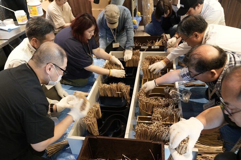 ホテルの顧客と共に、阿蘇の茅材を使ってオブジェを制作するワークショップの様子