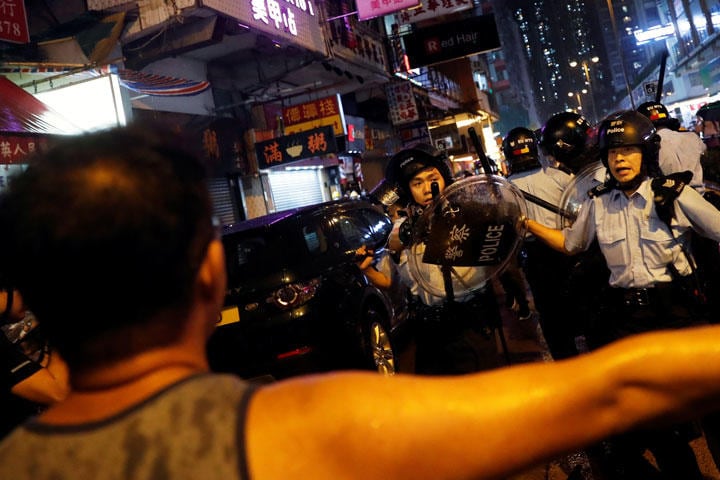 警官に銃口を向けられ両手を広げる男性（手前）（8月25日、香港セン湾区）　 Tyrone Siu-REUTERS