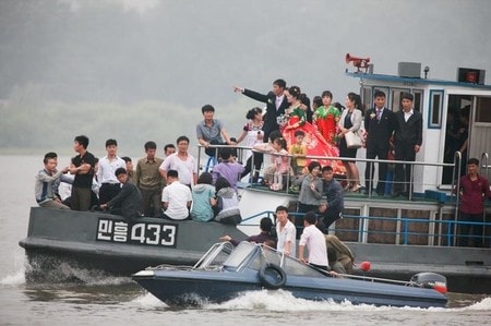　９月１３日、北朝鮮経済は、中国による燃料輸出削減など、貿易面での締め付けによる打撃を受けつつある兆候を見せている。写真は９日、中朝国境の鴨緑江で船に乗る北朝鮮の人々。中国丹東から撮影（２０１７年　ロイター/Jacky Chen）