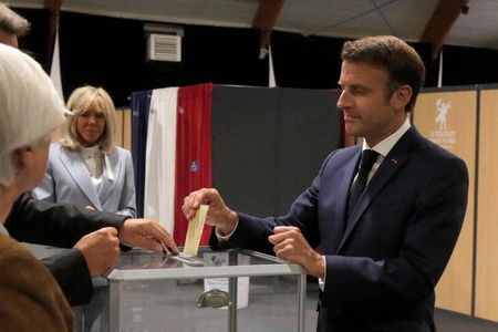 　フランス国民議会（下院、５７７議席）選挙の決選投票が１９日行われ、マクロン大統領率いる中道の与党連合が過半数を割り込む見通しとなった。写真右はル・トゥケで票を投じるマクロン氏。代表撮影（２０２２年　ロイター）