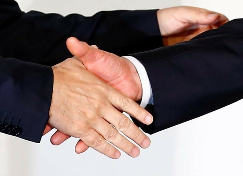 ５月２２日、燃費偽装で窮地に陥った三菱自動車が、日産自動車のカルロス・ゴーン社長という救世主を得て再生に動き出す。提携の会見で握手するゴーン社長（左）と益子会長、横浜で１２日撮影（２０１６年　ロイター／Thomas Peter）