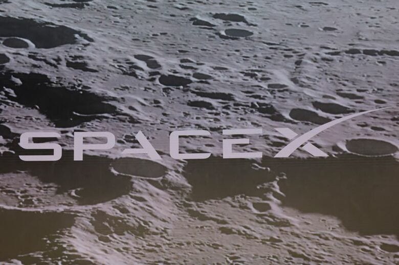 写真はスクリーンに表示された米宇宙開発企業スペースＸのロゴと月面のイメージ。6月12日、ニューヨークで撮影。REUTERS/Brendan McDermid