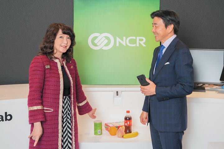 「モバイル・チェックアウト」機能を備えた最新のレジシステムの前で。レジ中央のボックスに商品を入れると、壁面に備えたAIカメラが商品を判別。その情報を顧客のスマホに送る仕組み。日本では未導入だが、米国大手スーパーで試験運用が開始されている。