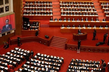 中国の李克強首相は、５日開幕した全国人民代表大会（全人代）の政府活動報告で、２０２１年の国内総生産（ＧＤＰ）成長率目標を６％を上回る水準に設定したと述べた。写真は演壇に立って同報告を行う李首相と大型スクリーンに映し出された同氏の映像。同日撮影。（２０２１年　ロイター／Carlos Garcia Rawlins）
