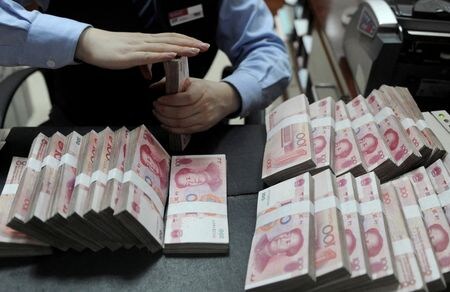 　７月３日、インドの製油業者がロシア産原油を輸入する際の決済通貨として人民元を利用し始めたと、関係者が明らかにした。欧米などの対ロ制裁を受けてドル決済が制限されていることが背景。写真は１００元紙幣を数える銀行員。２０１３年１月に安徽省で撮影された提供写真（２０２３年　ロイター）