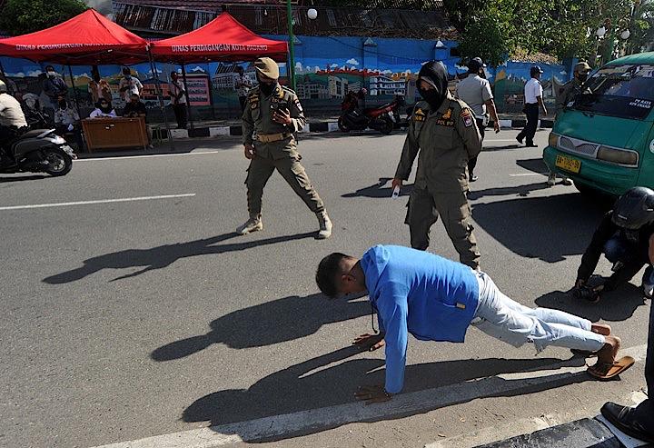 マスクをせず外出していた男が警察に見つかり罰を受け、記録撮影までされる。Antana Foto Agency - REUTERS