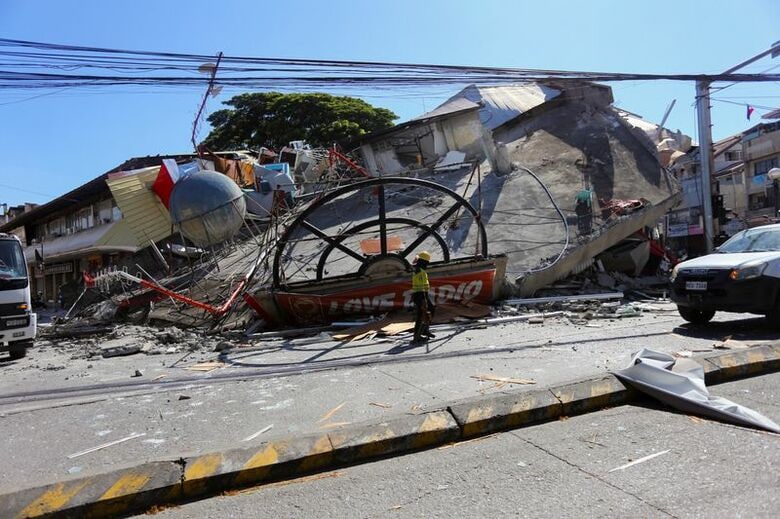 写真は８日、マグニチュード（Ｍ）７．８の地震発生後、倒壊した建物の近くを歩く作業員。フィリピン南部ジェネラルサントス市で撮影。REUTERS/Manman Dejeto