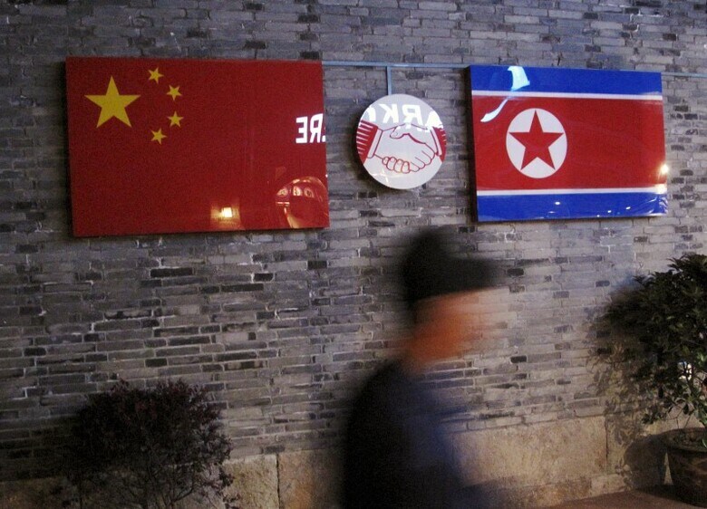 ９月１６日、北朝鮮に対する新たな制裁決議について、他の国連安全保障理事会メンバーと協議を始めたものの、中国は同盟国の核・ミサイル実験強化にどう対処すべきか、頭を悩ませている。写真は中国の国旗（左）と北朝鮮の国旗。中国・浙江省にある閉鎖された北朝鮮レストランで４月撮影（２０１６年　ロイター/Joseph Campbell）
