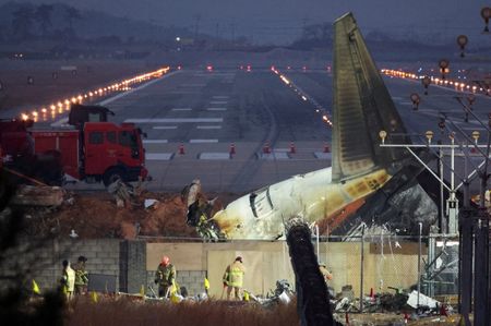 写真は滑走路付近に墜落した済州航空の機体と救助隊員ら。2024年12月、韓国の務安国際空港で撮影。REUTERS/Kim Hong-Ji