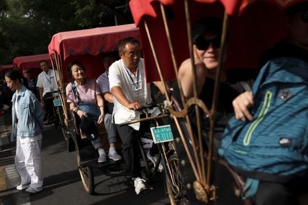 　１０月９日、中国文化観光省は、中秋節と国慶節に伴う大型連休中の国内旅行支出が８０９０億元（１１３５億２０００万ドル）だったと発表した。写真は、中国のゴールデンウィーク８連休の初日、国慶節に北京の什刹海地区で人力車に乗る観光客。１日撮影（２０２５年　ロイター/Florence Lo）