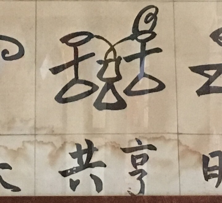 「シェアリング」を意味する雲南省ナシ族の象形文字。２人で１つのものをシェアしている図（筆者撮影）