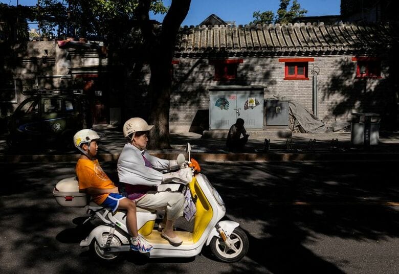 写真は電動バイクで走る人々。2026年8月、中国・北京で撮影。REUTERS/Maxim Shemetov