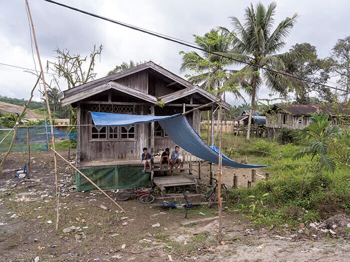 セパク・ラマ村の伝統的な家屋の前に座る少年たち。後方には舗装されたセパク川の土手が見える。ヌサンタラに大勢の人が移り住めば、この地域の暮らしも大きく変化するはずだが