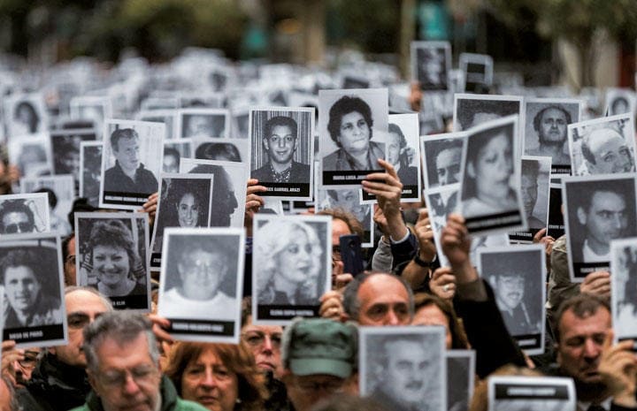 ブエノスアイレスで25年前に発生した爆破テロの犠牲者の遺影を掲げる人たち　Agustin Marcarian-REUTERS