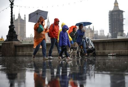 ６月１４日、  ジョンソン英首相は新型コロナウイルスの感染拡大を抑制する制限措置の解除を１カ月間延期すると発表した。インドで最初に見つかった新型コロナ変異株「デルタ」の感染拡大により、措置を講じなければ数千人が死亡する恐れがあると警告した。写真は６月４日、雨の中、ロンドン市内を歩く人達（２０２１年　ロイター／Henry Nicholls）