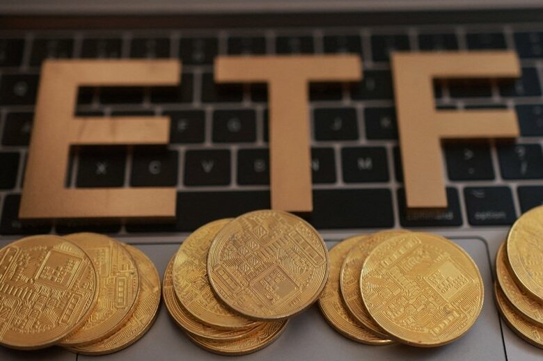 写真はキーボードに置かれた「ＥＴＦ（上場投資信託）」の文字と仮想通貨のイメージ。2025年10月撮影。REUTERS/Dado Ruvic