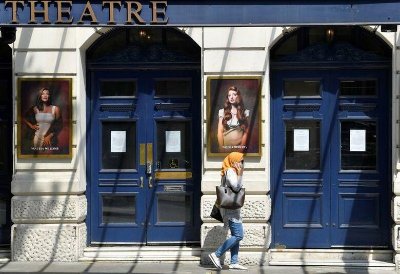 ジョンソン英首相は新型コロナウイルスの感染拡大とそれに伴うロックダウン(都市封鎖)で機能不全状態に陥っている文化・芸術部門を支援するため、15億7000万ポンド(19億6000万ドル)を投資すると発表した。写真は休業中の劇場前を歩く女性。6月23日、ロンドンで撮影(2020年　ロイター/Toby Melville)