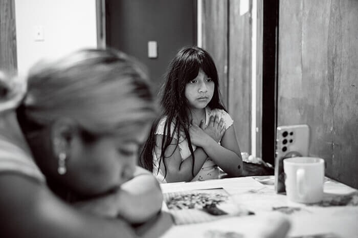 ニューヨーク・ブルックリンのアパートで、トラウマを克服するためのオンラインセラピーを母親の横で受ける10歳の移民の少女スカーレス