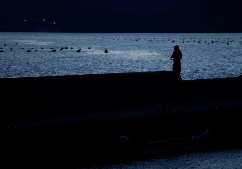 東日本大震災の発生から10年で投入された復興予算はおよそ31兆円。阪神淡路大震災復興事業費の2倍程度に相当する。このうち防潮堤や宅地整備などのインフラ整備には十分な費用対効果の検証が行われないまま、巨費が投入された経緯が浮かびあがってきた。写真は、岩手県陸前高田市の防波堤で釣りをする人。2月28日撮影（2021年　ロイター/Issei Kato）