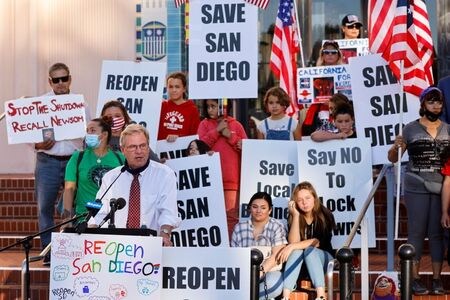 　１１月１９日、米国では新型コロナウイルスの新規感染者が再び急増しており、都市や地方で新たな行動制限を導入する動きが広がっている。写真はカリフォルニア州サンディエゴで、ビジネス活動の制限に抗議する人々。１６日撮影（２０２０年　ロイター/Mike Blake）