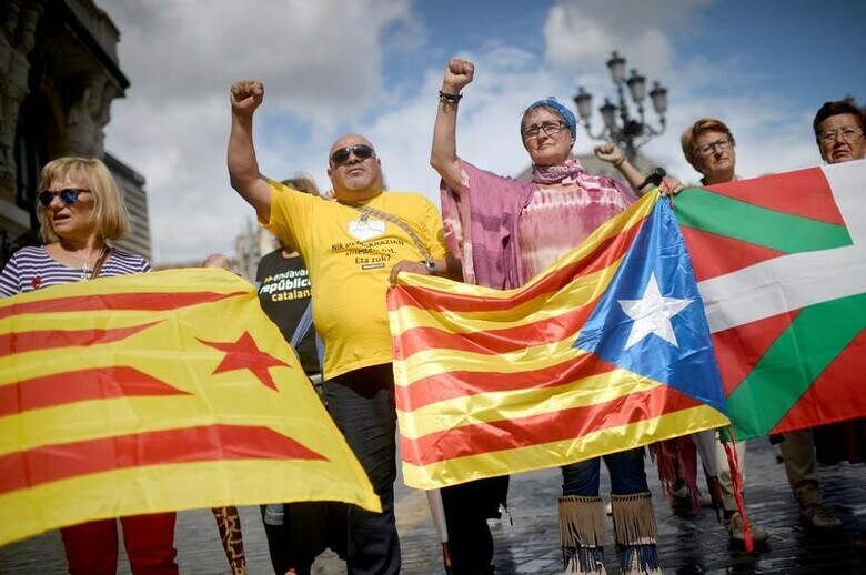 １０月９日、スペイン北東部のカタルーニャ自治州の分離・独立問題で同国政府と州政府が憲法上の衝突に直面するなか、どちらの側の政治家も、北部バスク地方に危機回避の解を見いだそうとしている。写真はカタルーニャ独立派の旗（左、中央）とバスクの旗（右）を掲げて独立を訴える市民。ビルバオで９月撮影（２０１７年　ロイター/Vincent West）