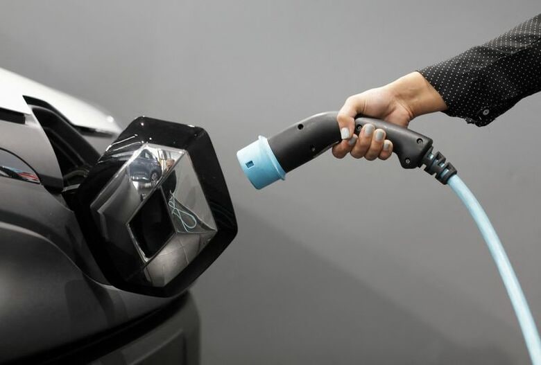 写真は電気自動車の充電ケーブルを手にする人。2020年10月、仏カーニュシュルメールにあるルノーの自動車販売店で撮影。REUTERS/Eric Gaillard