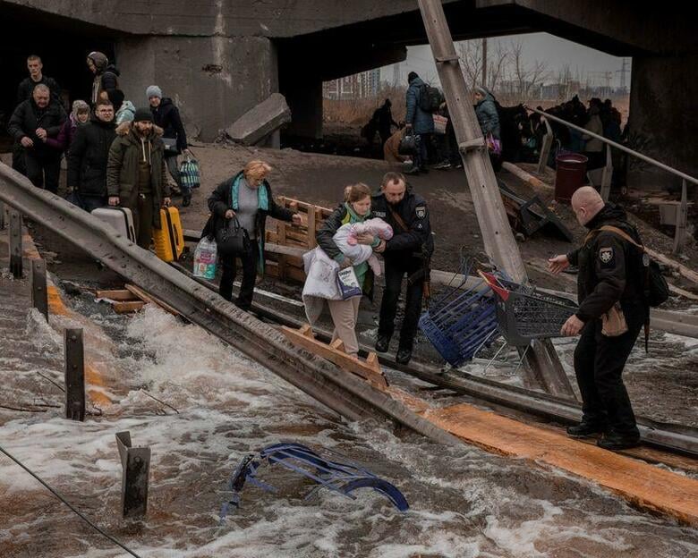ウクライナ北東部の都市スムイと首都キエフ近郊のイルピンで、民間人の退避が始まった。写真は7日、破壊された橋を渡ってイルピンから脱出する人々（2022年　ロイター/Jedrzej Nowicki/Agencja Wyborcza.pl）