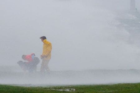 ８月２３日、  米東岸沖を北上していた熱帯暴風雨「アンリ」は２２日、勢力を弱めたものの北東部の一部が大雨となった。写真は２２日、アンリが上陸したロードアイランド州の公園で風雨や波にさらされる人（２０２１年　ロイター/Brian Snyder）