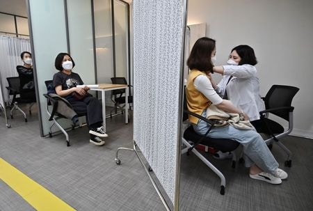 韓国当局は１６日、国民の２５％に新型コロナウイルスワクチンを少なくとも１回接種したとし、予定より２週間早く進展していることを明らかにした。写真はワクチン接種会場、ソウル、３月、代表撮影（２０２１年　ロイター）
