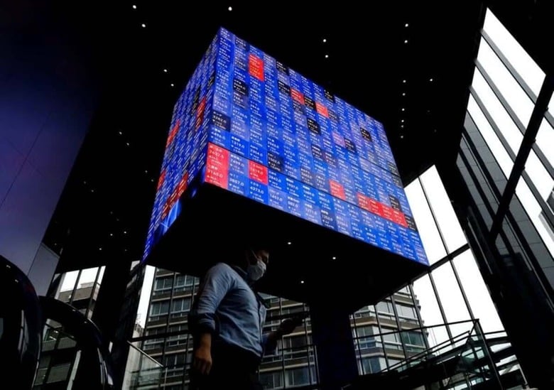 ８月５日、週明けの東京市場は、米景気後退懸念の高まりで、円高・株安・金利低下が一段と進んでいる。写真は株価ボードの下を歩く男性。都内で２０２２年６月撮影（２０２４　ロイター／Issei Kato）