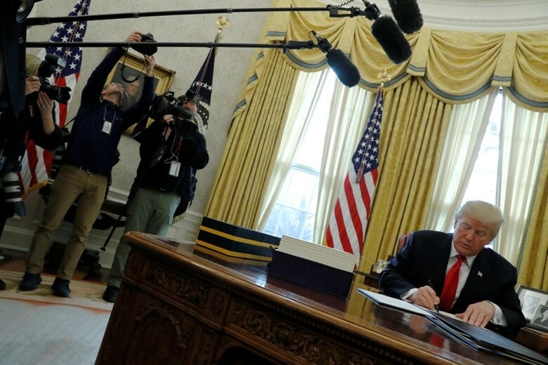 １２月２２日、１兆５０００億ドルの減税を実現する税制改革法案に署名した。前日に議会が可決した新たなつなぎ予算案も承認した。写真は同日ホワイトハウスでつなぎ予算に署名するトランプ大統領。（２０１７年　ロイター/Jonathan Ernst）