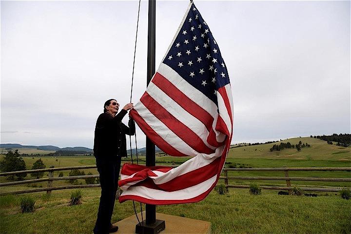 米国のトランプ大統領が看板政策として選挙公約に掲げていたのは、メキシコとの国境に「壁」を築くという構想だった。写真は、モンタナ州の農場で国旗を掲げるアーリン・マッカイさん。6月28日撮影（2019年　ロイター/Tommy Martino）