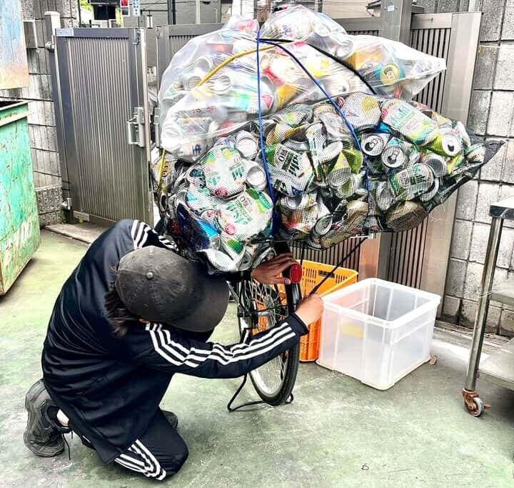 アルミ缶の袋を自転車から降ろす様子