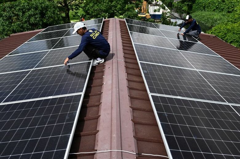 フィリピンのカウィットで、住宅の屋根にソーラーパネルを設置する作業員ら。6月26日撮影。REUTERS/Noel Celis