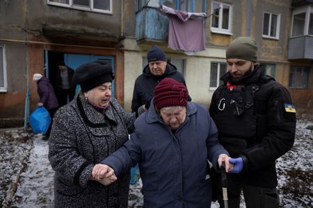 　２月２１日、ウクライナ東部ドネツク州の要衝アブデーフカを先週掌握したロシア軍は近隣の町への攻撃を続けている。写真はアブデーフカの自宅から避難する女性を助けるボランティアら。２０日撮影（２０２４年　ロイター/Thomas Peter）