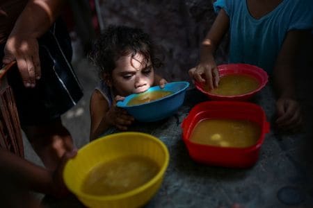 　７月２４日、国連の国際農業開発基金（ＩＦＡＤ）のアルバロ・ラリオ総裁は、気候変動による影響と金融・政治双方の怠慢のために、２０３０年の時点で６億人近い人々が飢餓状態に陥るとの見方を示した。写真はベネズエラのマラカイボでスープを飲む子ども。６月１２日撮影（２０２４年　ロイター/Gaby Oraa）
